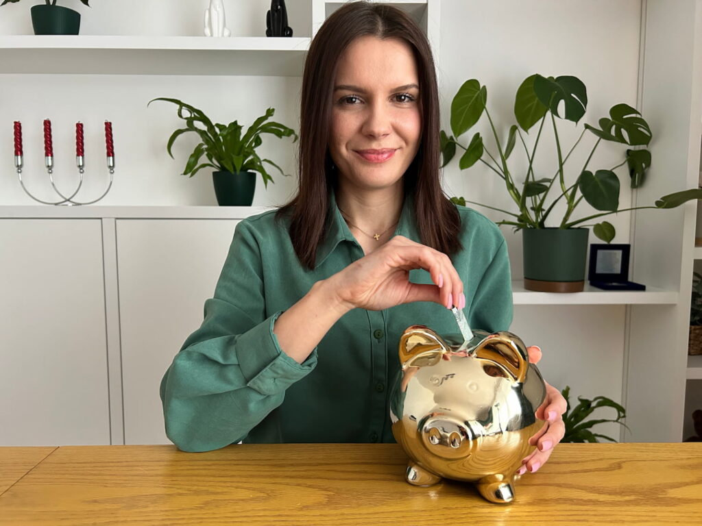 Ekspert Kredytowy Weronika Golec wkłada banknoty do skarbonki